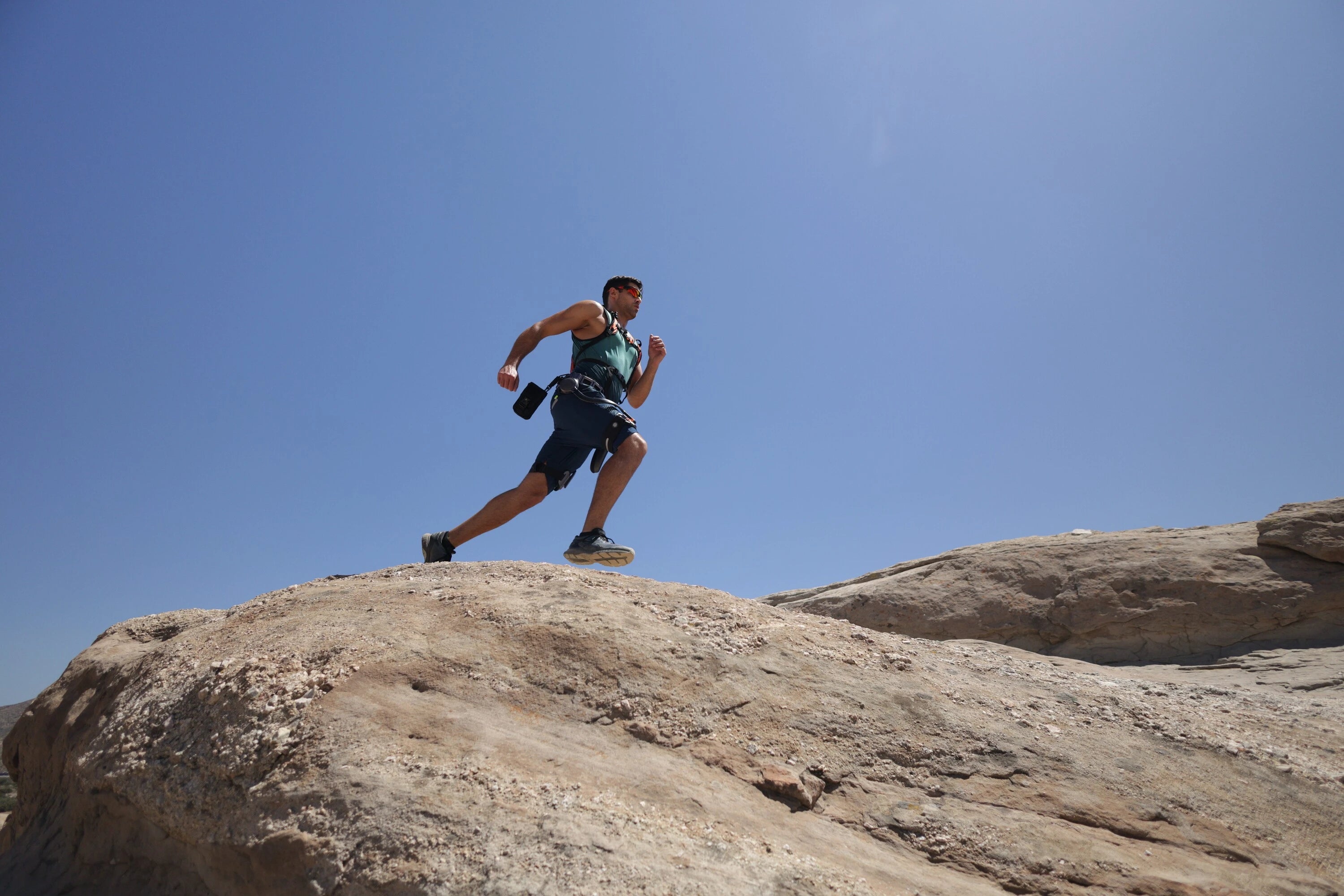 Man wearing Ascentiz H exoskeleton module running fast over rocky terrain