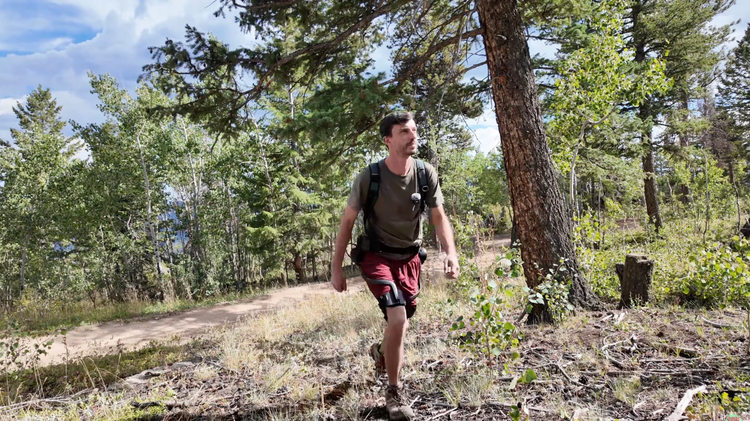 Man hiking up a mountain wearing the Ascentiz robot legs to reduce fatigue.