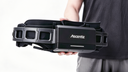Studio shot of a model holding the Ascentiz exoskeleton waist belt with the intelligent battery pack mounted, showcasing the integrated wearable power design against a white background.