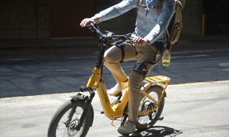 A man is riding a bike in city while wearing the Ascentiz hip exoskeleton.