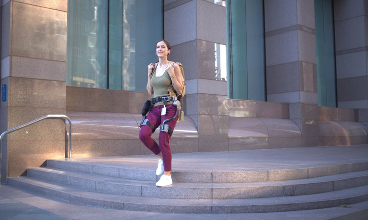 A woman travels through the city buildings wearing the Ascentiz hip exoskeleton to reduce fatigue.