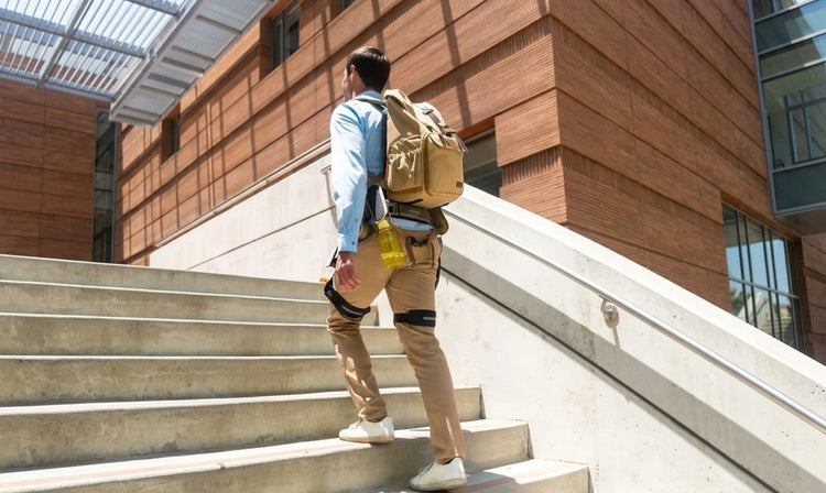 A man is climbing up stairs while wearing the Ascentiz hip exoskeletons legs to help with leg lifting.
