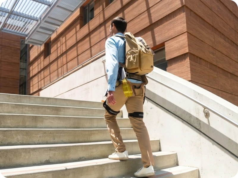 Man climbs up staircase with  assistance of Ascentiz H model exoskeleton. 