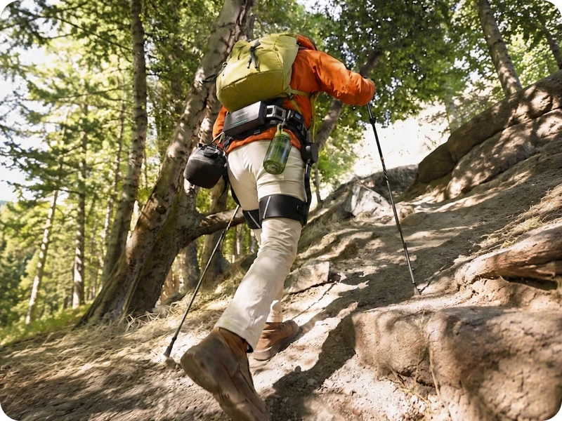 Man hiking up a trail wearing the Ascentiz hip exoskeleton to enhance his steps.